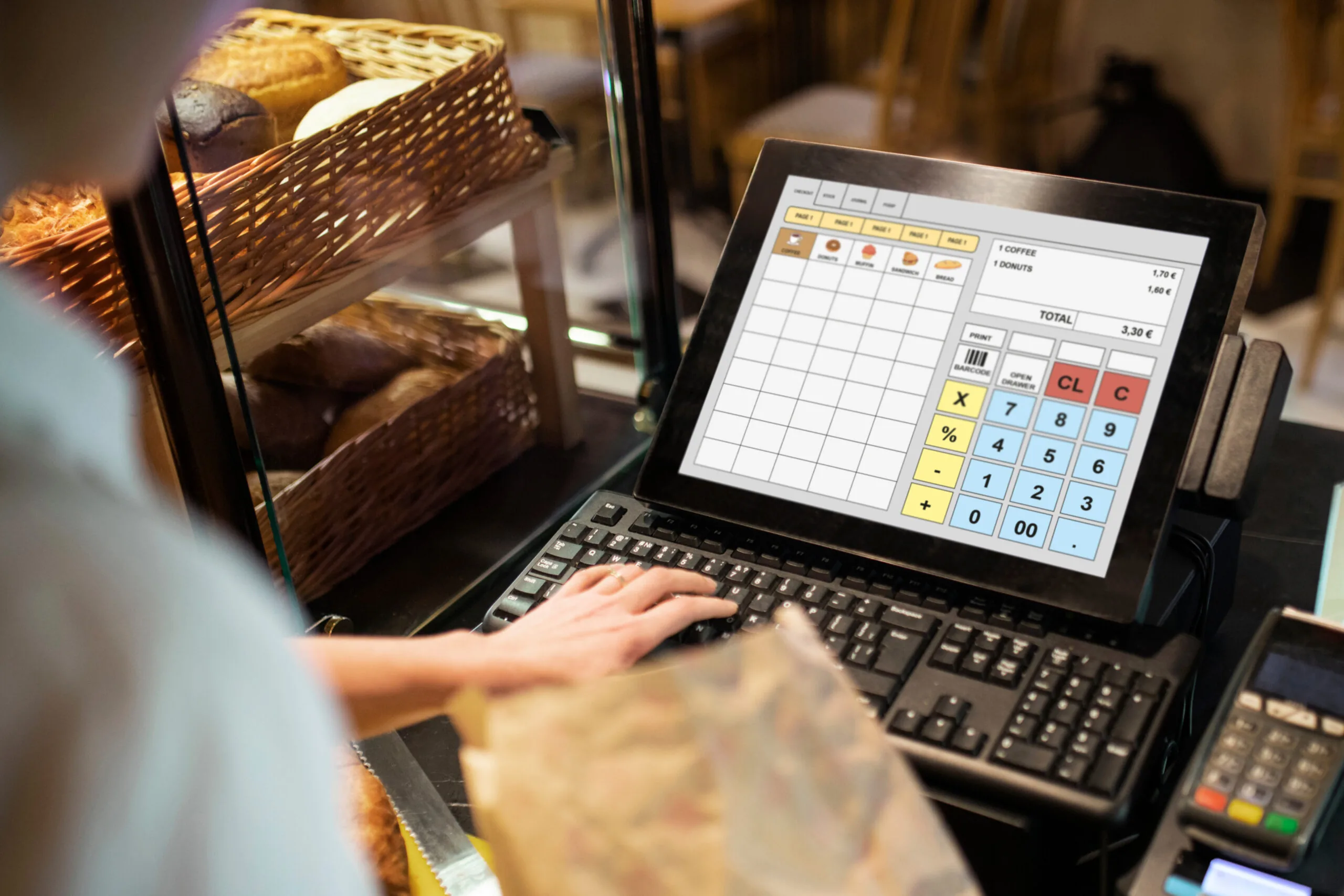 A cashier ringing up a sale on a POS register in a bakery