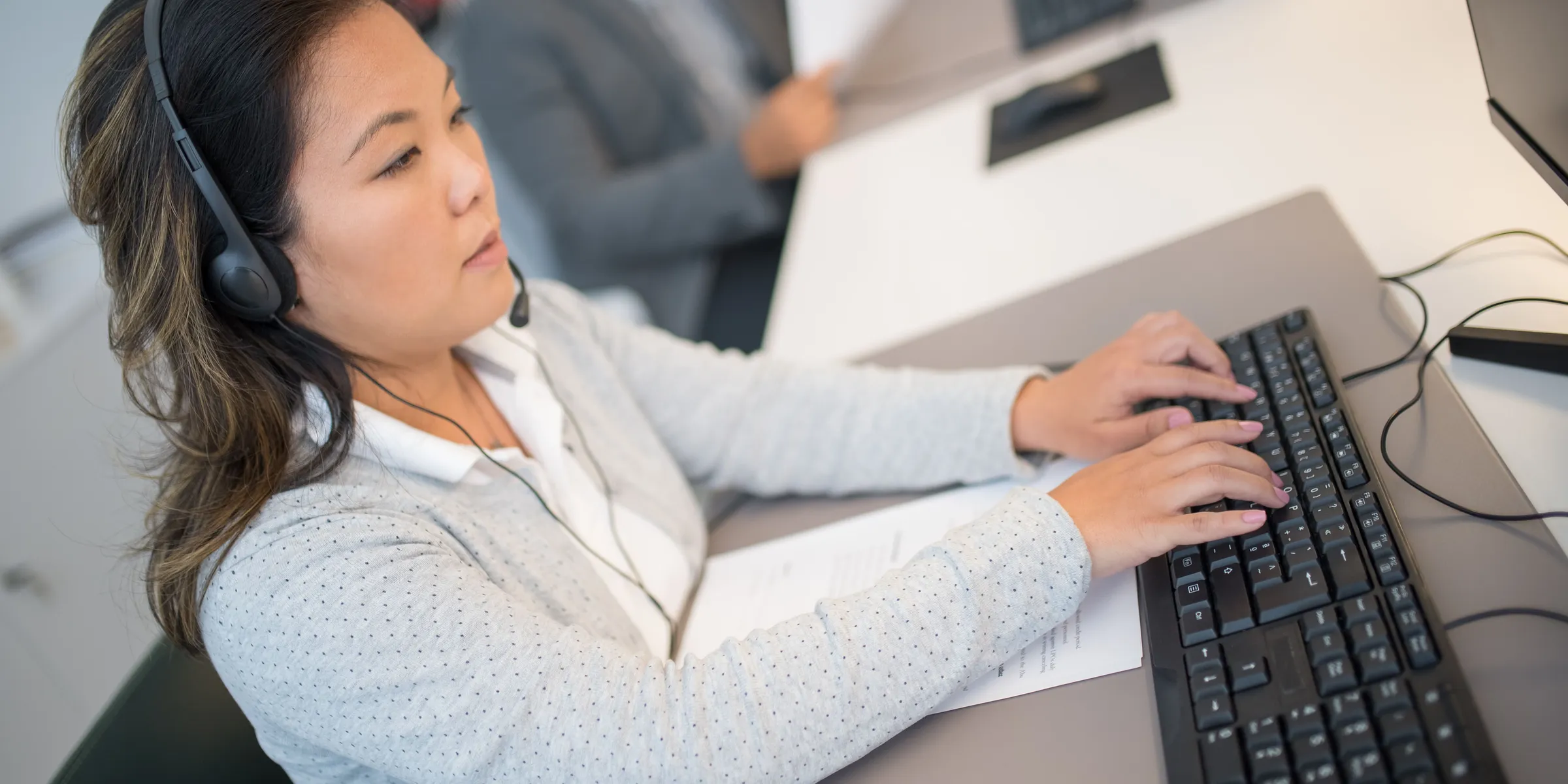 A call taker wearing a headset, typing at a computer