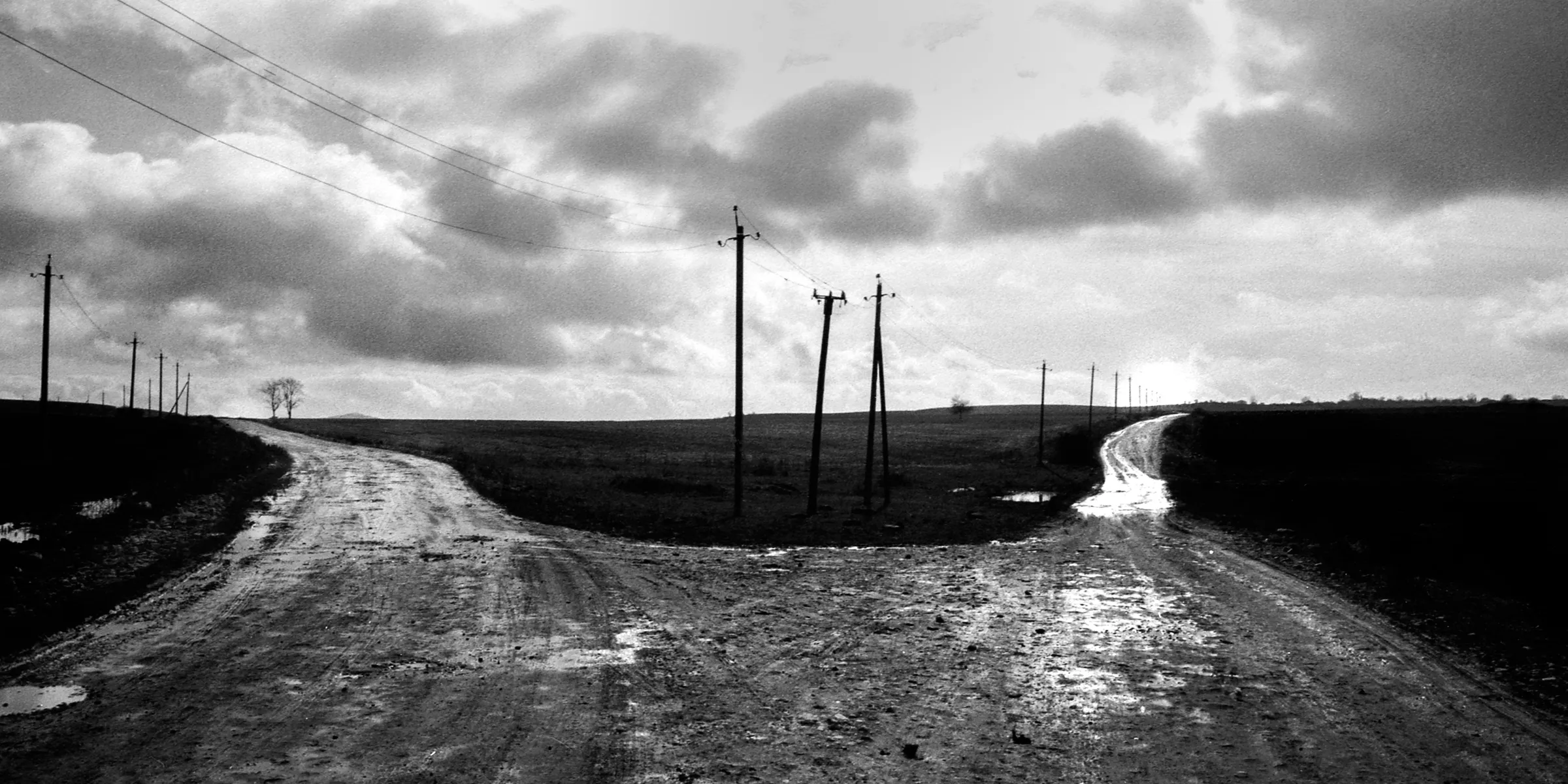 A fork in a dirt road under a cloudy sky