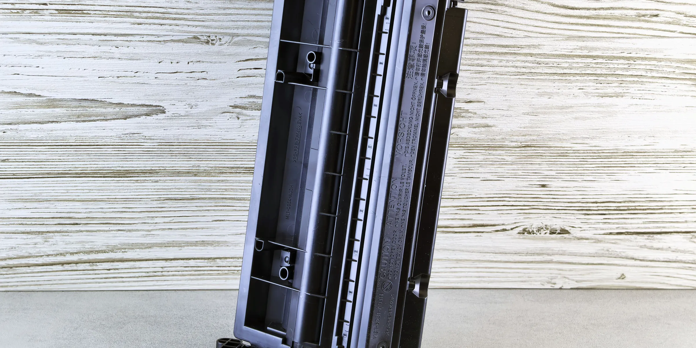 A toner cartridge standing on a wooden surface