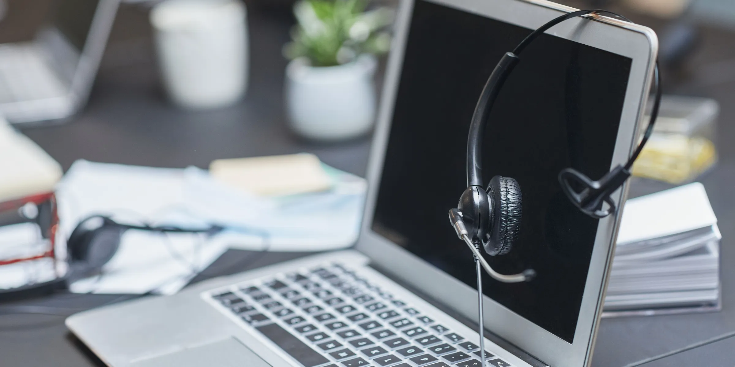 A headset resting on a laptop at an office desk